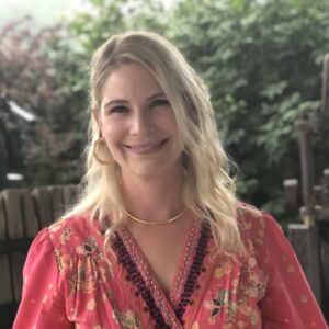 Photo of Ariel PJ Stewart, with blonde hair and a pink blouse.